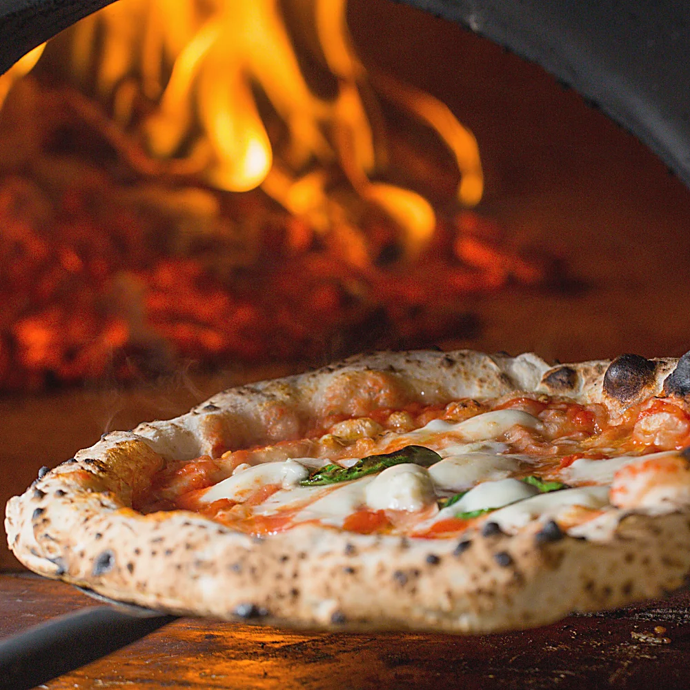 Pizza appena sfornata davanti alla fiamma del forno