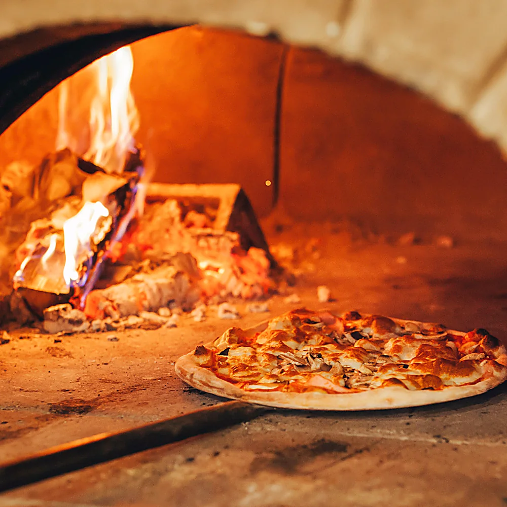 Pizza che cuoce nel forno con la fiamma viva